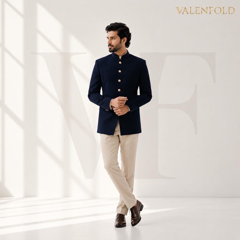Puede incluir: Chaqueta azul marino con cuello mao y botones dorados, combinada con pantalones beige y zapatos de cuero marr&oacute;n. La chaqueta tiene cuello mandar&iacute;n y es de la marca VALENFOLD.