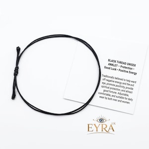 May include: A thin black thread anklet with an adjustable sliding knot closure. It is displayed next to a white card featuring the text: BLACK THREAD UNISEX ANKLET - Protection - Good Luck - Positive Energy. The card also includes the brand name EYRA.