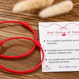 May include: Two red string bracelets with adjustable knots and a white rectangular card featuring the text Red String of Fate, along with descriptive bullet points about luck, protection, and connection, ending with the text Tie Wish Love.