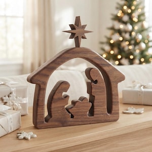 May include: A dark brown wooden nativity scene silhouette featuring a stable structure with a star at the peak. The cutout design depicts three figures representing a family unit, crafted from smooth wood with visible grain patterns throughout.