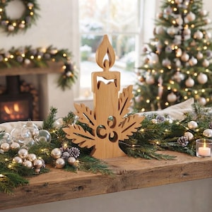 May include: A light brown wooden candle decoration featuring a stylised flame at the top and intricate leaf-shaped cutouts along the sides. The piece is crafted from a single piece of wood with a smooth finish and a flat base for stability.