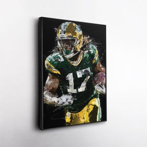 May include: Framed artwork depicting a football player in a green and yellow uniform, number 17, running with the ball. The artwork has a painterly style with black and white accents, set against a black background.