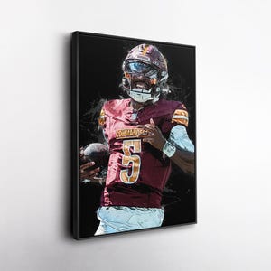 May include: Framed art print of an American football player in a burgundy and gold uniform. The player is holding a football and wearing a helmet. The jersey displays the number 5 in gold. The background is black with white paint splatter.