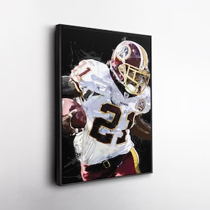 May include: Framed artwork of a football player in a burgundy and gold helmet and uniform, holding a football. The player's jersey displays the number 21 in large black numerals. The background is black with white paint splatters.