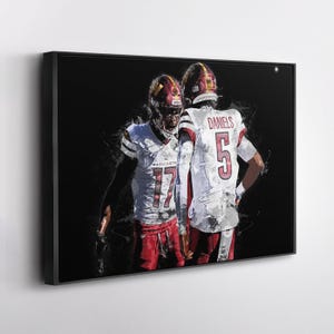 May include: Framed artwork depicting two American football players in white and burgundy uniforms. One player wears the number 17, the other number 5. Both wear helmets. The background is black with white paint strokes.