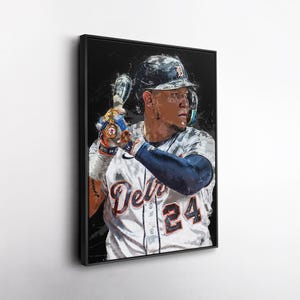 May include: Framed art print of a baseball player in a Detroit Tigers uniform, holding a bat. The player is wearing a helmet and batting gloves. The jersey displays "Detroit" and the number "24". The artwork has a painterly style.