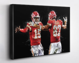 May include: Framed artwork featuring two football players in red uniforms with white pants. One player wears the number 15, the other number 87. The background is black with white paint splatter effects.