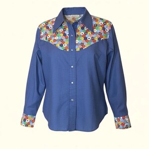 May include: A blue long-sleeve shirt with a colorful patchwork design on the yoke, collar, and cuffs. The shirt has a button-down front and a classic collar. The patchwork features a variety of shapes and colors, including red, yellow, blue, and green.