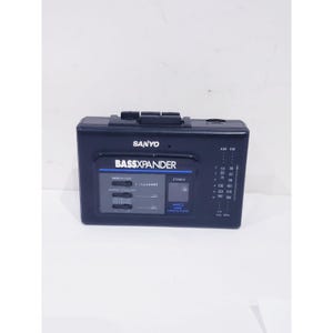 May include: A dark blue Sanyo portable radio cassette player featuring a Bassxpander graphic equaliser with three sliding controls, a stereo indicator light, and a vertical AM/FM radio frequency tuning scale printed on the front panel.