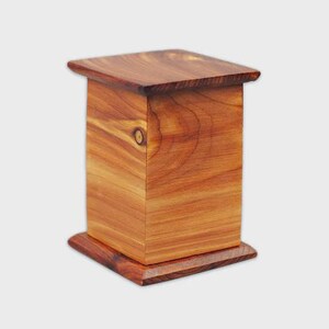May include: A handcrafted wooden box with a square top and base. The box is rectangular with a warm, reddish-brown color and visible wood grain. The design features a simple, elegant aesthetic, suitable for various uses.