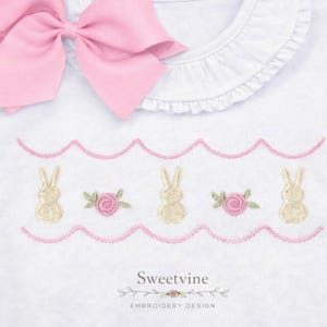May include: White baby onesie with a pink bow and a scalloped trim. The onesie features embroidered bunnies and roses in cream and pink. The text "Sweetvine EMBROIDERY DESIGN" is at the bottom.
