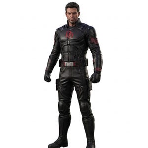 Puede incluir: Una figura de acción altamente detallada de un personaje con un traje táctico negro con detalles en rojo. El traje presenta un logotipo DD rojo prominente en el pecho, un cinturón utilitario, rodilleras y guantes negros.