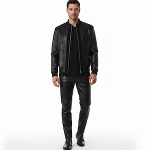 Puede incluir: Conjunto negro de chaqueta y pantalón de cuero texturizado. La chaqueta, de estilo bomber, tiene cierre de cremallera y puños acanalados. El pantalón es entallado. El conjunto es completamente negro, creando un look elegante y coordinado.