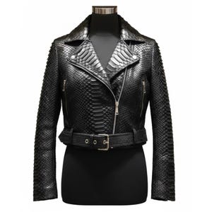 Puede incluir: Chaqueta de cuero negro con estampado de piel de serpiente. La chaqueta tiene cuello con solapas, cierre de cremallera asimétrico y cinturón en la cintura. Tiene dos bolsillos con cremallera y hebilla plateada.