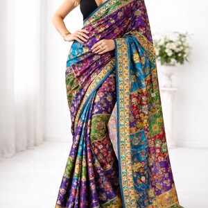 May include: A colourful saree in purple, blue, green, and gold, with a floral pattern. The fabric has detailed borders. The saree is draped, displaying its rich colours and intricate patterns.