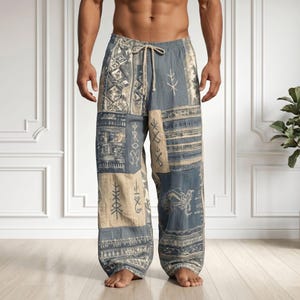 May include: Loose-fitting trousers featuring a patchwork design in shades of blue and beige. The fabric displays various printed geometric patterns and symbols. The trousers include an elastic waistband with a functional beige drawstring tie.