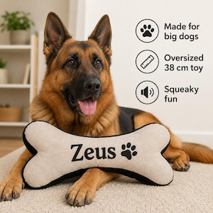 May include: A beige bone-shaped dog toy with black trim, featuring the name Zeus and a paw print icon embroidered in black. The toy is labelled as an oversized 38 cm toy, made for big dogs, and provides squeaky fun for pets to play with.