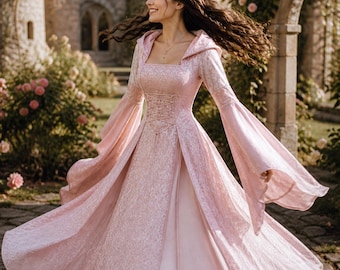 May include: A light pink medieval-style dress with a square neckline, long, flared sleeves, and a hooded cape. The dress features a corset-style bodice and a flowing skirt. The background includes a castle and garden setting.