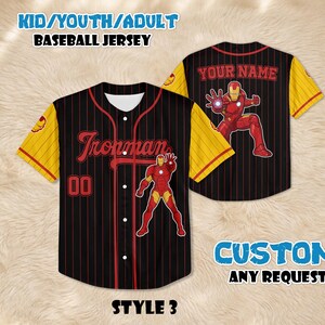 Puede incluir: Camiseta de b&eacute;isbol negra con finas rayas rojas, mangas amarillas y un gr&aacute;fico de Iron Man. La camiseta presenta el texto "Ironman" y el n&uacute;mero "00" en la parte delantera. La parte posterior de la camiseta tiene el texto "YOUR NAME".