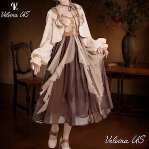 May include: A layered dress in shades of brown and beige, featuring a ruffled skirt and a decorative bodice. The dress is paired with a matching bolero jacket with long sleeves. The image includes the text "Velvina US".