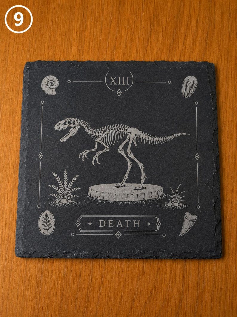 Puede incluir: Un posavasos cuadrado de pizarra negra con el grabado de un esqueleto de dinosaurio sobre una base circular. El dise&ntilde;o incluye el n&uacute;mero romano XIII en la parte superior, la palabra DEATH en la inferior y f&oacute;siles en las esquinas.