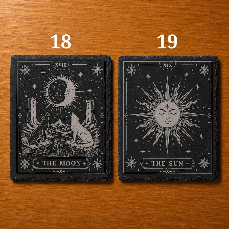 May include: Two rectangular black slate coasters featuring white engraved designs. The left coaster, labeled 18, depicts The Moon with wolves, towers, and a crustacean. The right coaster, labeled 19, depicts The Sun with a central face and rays.