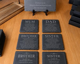 Könnte beinhalten: Eine Sammlung quadratischer Schieferuntersetzer mit rauen, natürlichen Kanten, die jeweils mit weißem Text graviert sind, der Familienrollen wie Mum, Dad, Brother und Sister beschreibt. Ein größeres Schieferschild zeigt die Firmendaten von Shipyard Belfast.