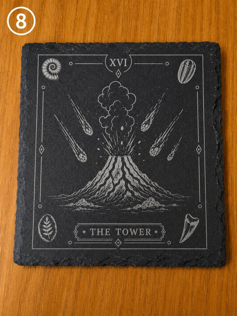 Puede incluir: Un posavasos cuadrado de pizarra negra con un grabado l&aacute;ser blanco de una erupci&oacute;n volc&aacute;nica y meteoritos. El dise&ntilde;o incluye el n&uacute;mero romano XVI, el texto THE TOWER e ilustraciones de f&oacute;siles en las esquinas del borde decorativo.