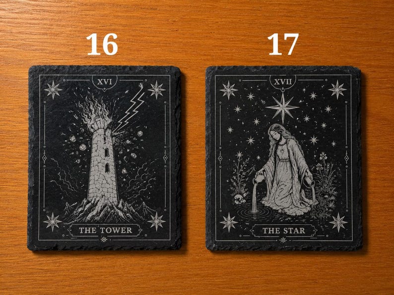 May include: Two rectangular black slate coasters featuring white engraved tarot card designs. The left coaster displays The Tower, labeled XVI, with a lightning bolt striking a stone tower. The right coaster shows The Star, labeled XVII, with a figure pouring water into a pool under a large star.