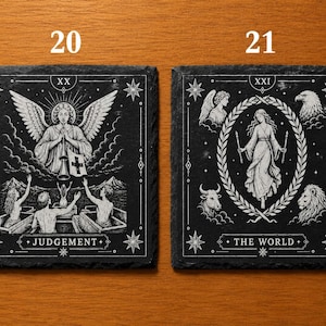 May include: Two square black slate coasters featuring white engraved tarot card designs. The left coaster shows Judgement with an angel and figures rising from coffins. The right coaster shows The World with a central figure, laurel wreath, and four animal heads.