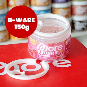 Könnte beinhalten: Ein durchsichtiger Kunststoffbehälter mit More Chunky Flavour Strawberry Cookie Crumble Pulver, weißem Deckel und einem kleinen Messlöffel. Das Etikett zeigt rosa und weißen Text mit Erdbeergrafiken. Ein roter Kreis zeigt B-WARE 150g.