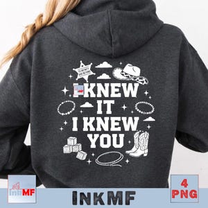 May include: A dark charcoal gray hooded sweatshirt featuring a white graphic on the back. The text reads I KNEW IT I KNEW YOU, surrounded by illustrations of a sheriff star with the text TO INFINITY AND BEYOND, a cowboy hat, blocks, a lasso, and stars.