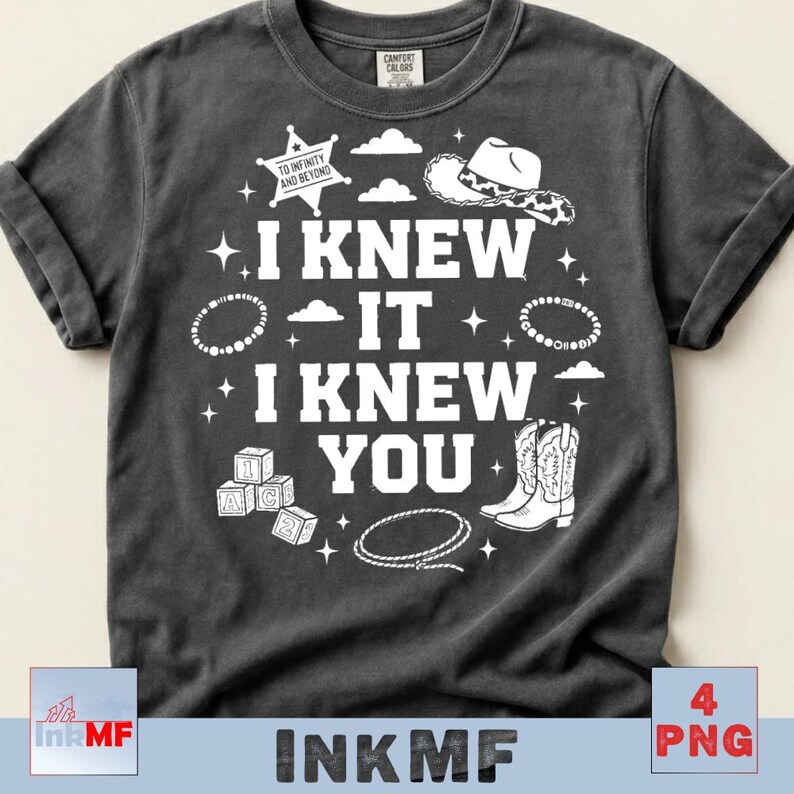 May include: A charcoal gray short-sleeve t-shirt featuring white graphic prints including a sheriff badge with the text TO INFINITY AND BEYOND, a cowboy hat, cowboy boots, a lasso, alphabet blocks, and the text I KNEW IT I KNEW YOU.