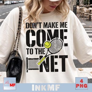 Op de afbeelding: Een off-white t-shirt met een zwarte grafische print met de tekst DON'T MAKE ME COME TO THE NET. Het ontwerp bevat een gele tennisbal, een zwart tennisracket en een kleine zwarte tennisnet-afbeelding met een verweerde textuur.