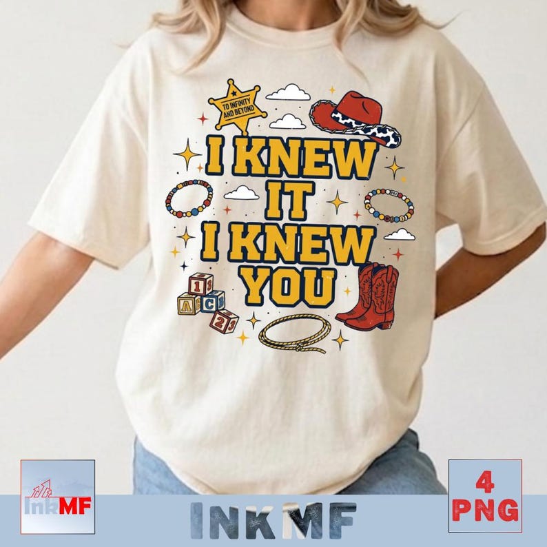 May include: A cream-colored t-shirt featuring a graphic print with the text I KNEW IT I KNEW YOU in yellow. The design includes a sheriff star, a red cowboy hat, alphabet blocks, a lasso, beaded bracelets, and small cloud and star icons.