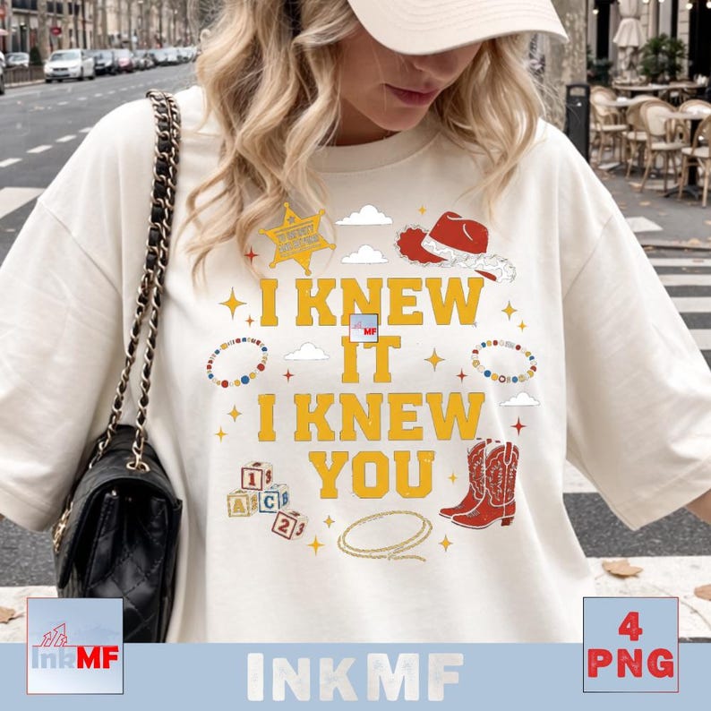 May include: A cream-colored t-shirt featuring the yellow text I KNEW IT I KNEW YOU. The graphic includes a yellow sheriff star, a red cowboy hat, red cowboy boots, a lasso, alphabet blocks, beaded bracelets, clouds, and small yellow stars.