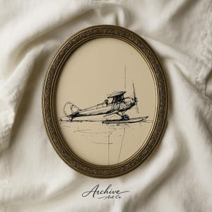 May include: An oval framed print featuring a pen and ink drawing of a vintage biplane. The artwork is in black and white, set against a cream-colored background. The frame is gold-toned with an ornate design. The text "Archive Art Co." is at the bottom.