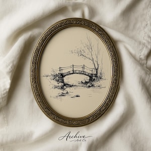 May include: An oval framed art print featuring a black and white pen and ink drawing of a stone bridge over a stream. The frame is gold-toned with an ornate border. The print is on a cream-colored background. The text "Archive Art Co." is at the bottom.