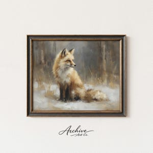 May include: Framed art print of a red fox sitting in the snow. The fox has a fluffy tail and is set against a backdrop of a forest. The artwork is in a dark wooden frame. The text "Archive Art Co." is in the bottom left corner.