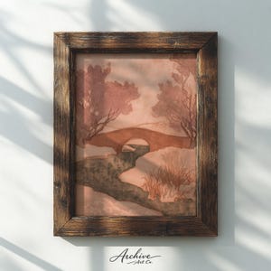 May include: A framed watercolor print of a landscape featuring a bridge over a stream, with trees and foliage in muted tones of brown and pink. The frame is a dark, textured wood. The text "Archive Art Co." is in the bottom corner.
