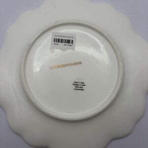 Puede incluir: Plato blanco de Anthropologie con borde festoneado. La parte inferior del plato presenta el nombre de la marca, una etiqueta con c&oacute;digo de barras y texto que indica que fue fabricado en China. El plato tiene un acabado liso y brillante.