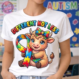Könnte beinhalten: Weißes T-Shirt mit dem Text "DIFFERENT NOT LESS" und einer Cartoon-Kuh, die ein farbenfrohes Puzzlerband hält. Die Kuh hat eine passende Schleife und blaue Augen. Das Design fördert das Bewusstsein für Autismus.