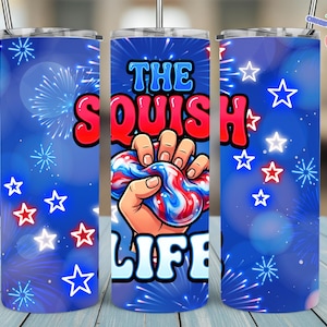 Könnte beinhalten: Drei Edelstahlbecher mit blauem Hintergrund und einem Design mit Feuerwerk, Sternen und dem Text "THE SQUISH LIFE". Der mittlere Becher zeigt eine Hand, die ein rot-weiß-blaues Squishy-Spielzeug drückt.