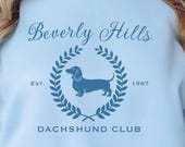 → View on Etsy: Beverly Hills Dachshund Club Sweatshirt, Cute Doxie Lover shirt, Trendy Dog Mom Gift, Preppy Wiener Dog Crewneck Beverly Hills Dachshund Club Sweatshirt, Cute Doxie Lover shirt, Trendy Dog Mom Gift, Preppy Wiener Dog Crewneck
