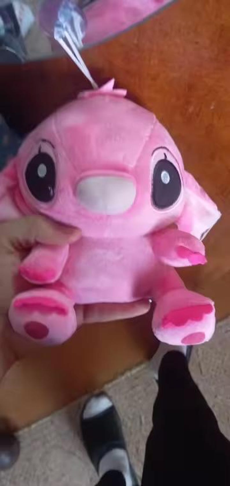 May include: A pink plush toy with large black eyes, a white muzzle, and large ears. The toy has pink accents on its hands and feet. The toy is held in a person's hand.