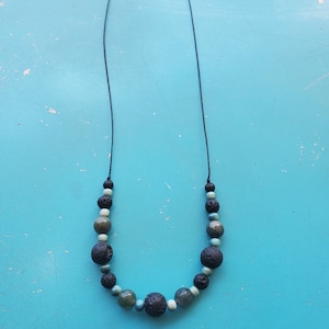May include: A black cord necklace with alternating black lava rock and green and blue agate beads.