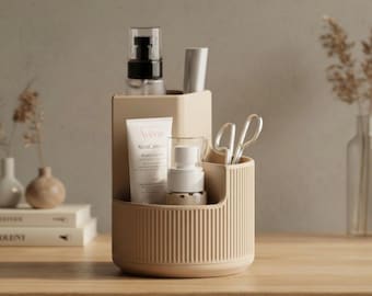 May include: A beige, ribbed cosmetic organizer with multiple compartments. It holds various beauty products, including a tube of Avene XeraCalm cream, a pump bottle, and a pair of silver scissors. The organizer sits on a wooden surface.