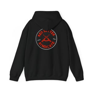 May include: Black hoodie with a red and white circular graphic on the back. The graphic features crossed rifles and the text "RED LETTER SYNDICATE" with "SINCE 2024" in a circular design. The hoodie has a hood and long sleeves.