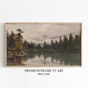 Könnte beinhalten: Gerahmtes Landschaftsgemälde, das eine ruhige Seeszene mit hohen Bäumen und Bergen im Hintergrund zeigt. Das Kunstwerk verwendet gedämpfte Töne von Grün, Braun und Grau, mit Reflexionen im Wasser. Der Text "PREMIUM FRAME TV ART" ist sichtbar.