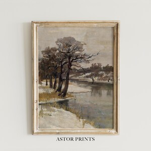May include: A framed vintage landscape painting depicting a winter scene with a river and snow-covered banks. Bare trees line the water's edge under a cloudy sky. The artwork is signed "ASTOR PRINTS" at the bottom.